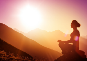 Man meditating on a mountainside at sunrise